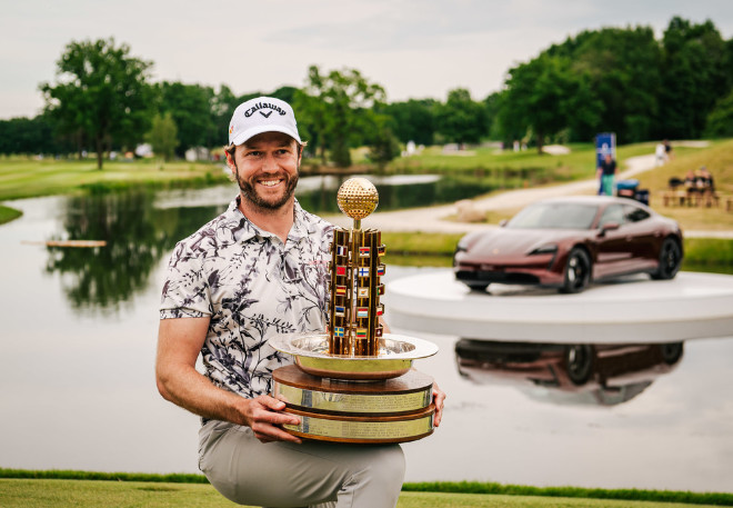 Porsche European Open 2022 Sieger Kalle Samooja. Im Hintergrund auf der Plattform im See steht ein Taycan mit elektrischer Reichweite von 371 bis 505 km. Fotocredit: Porsche