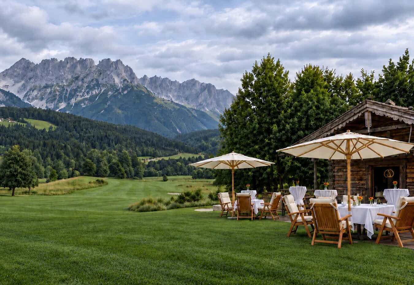 Halfway-Hütte des Golfclubs Wilder Kaiser mit gedeckten Tischen und Blick auf das Bergmassiv.