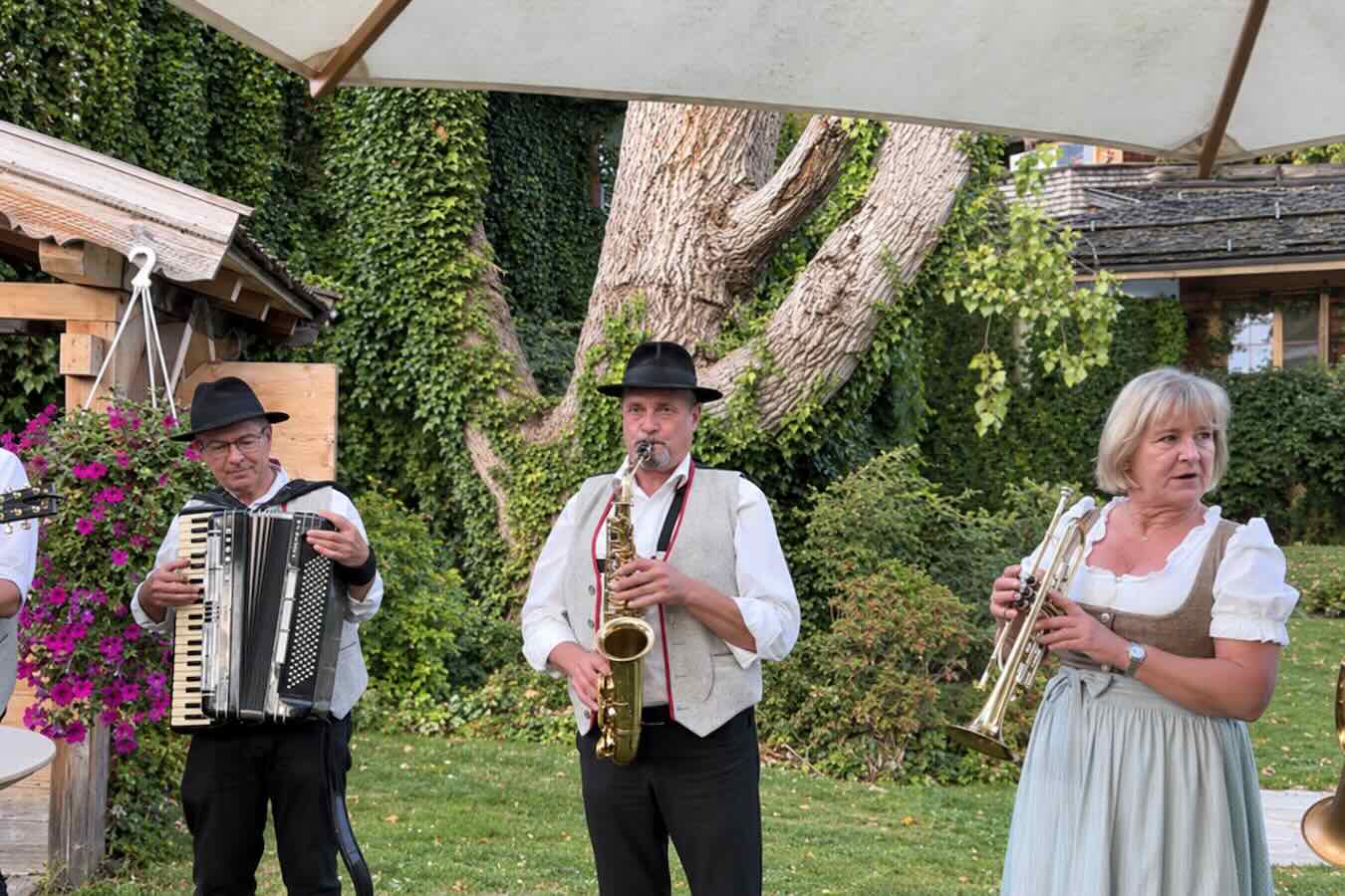 Stanglwirt-Hoteldirektorin Trixi Moser mit Trompete sowie zwei Tiroler Musiker mit Saxofon und Akkordeon.